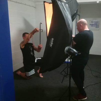 Photographer Guy photographs a person kneeling on the floor in front of studio lights