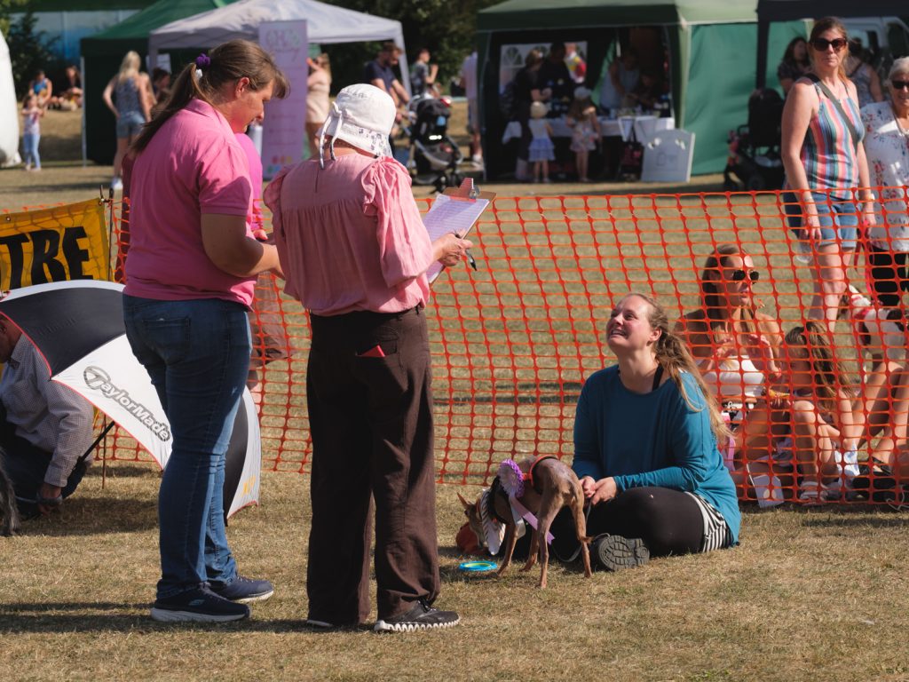 Two judges talk to a woman with a small dog on a lead