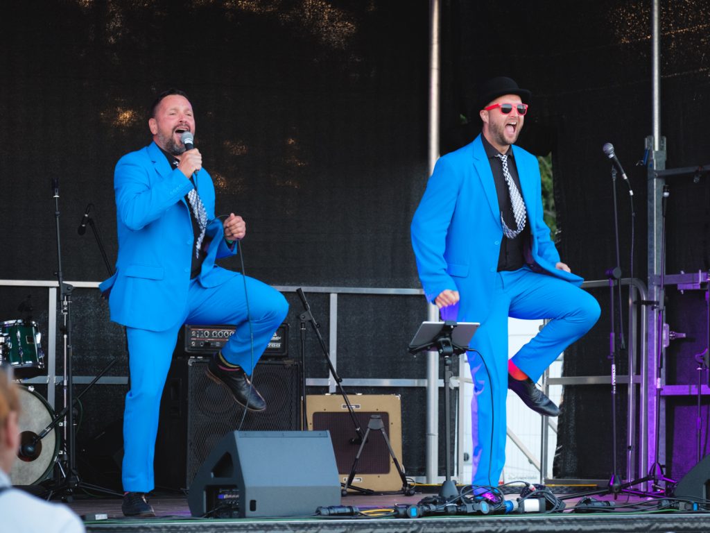 Two men in suits on a stage, dancing in sync